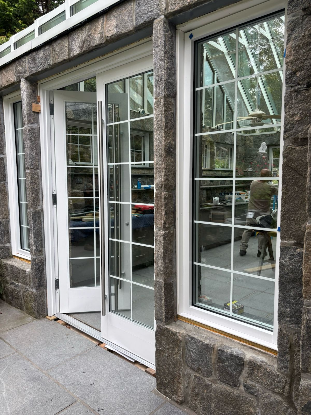 Custom French doors with grid pattern glass installed on stone facade building
